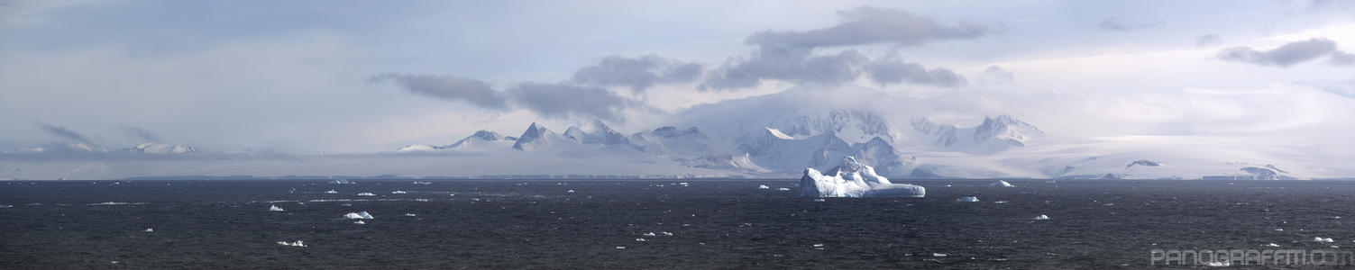 Large Iceberg Drifting in Suspiros Bay - Deeper into the bay icebergs are seen passing in front of a misty mountainous backdrop