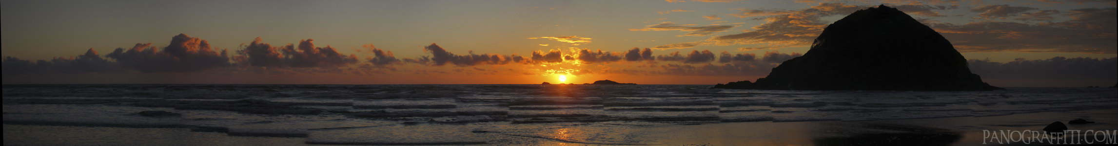 Paritutu Centennial Park Sunset Dark - A beautiful sunset framed by large rocks on a beach near New Plymouth